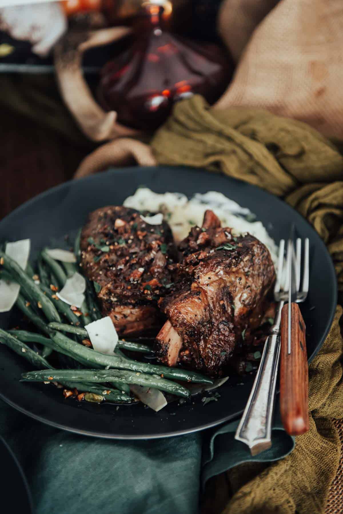 A black plate with green beans and meat on it.