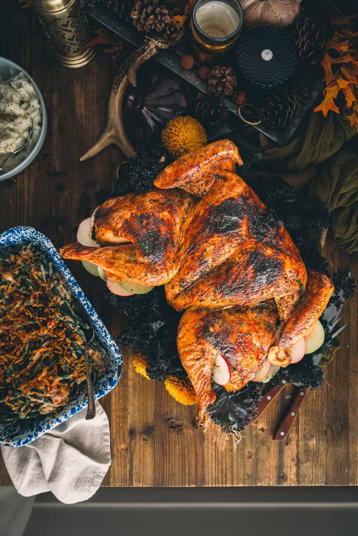 Roasted spatchcocked turkey on a table with green beans.