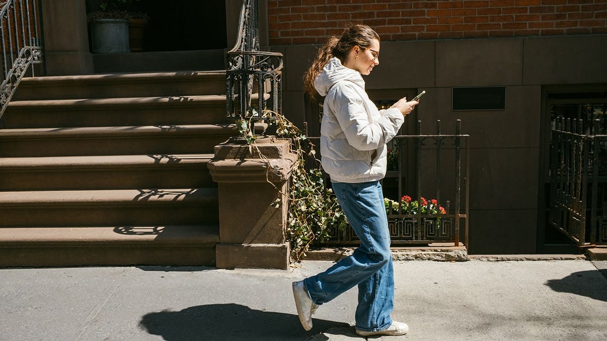 Teenage girl using smartphone while walking in New York City