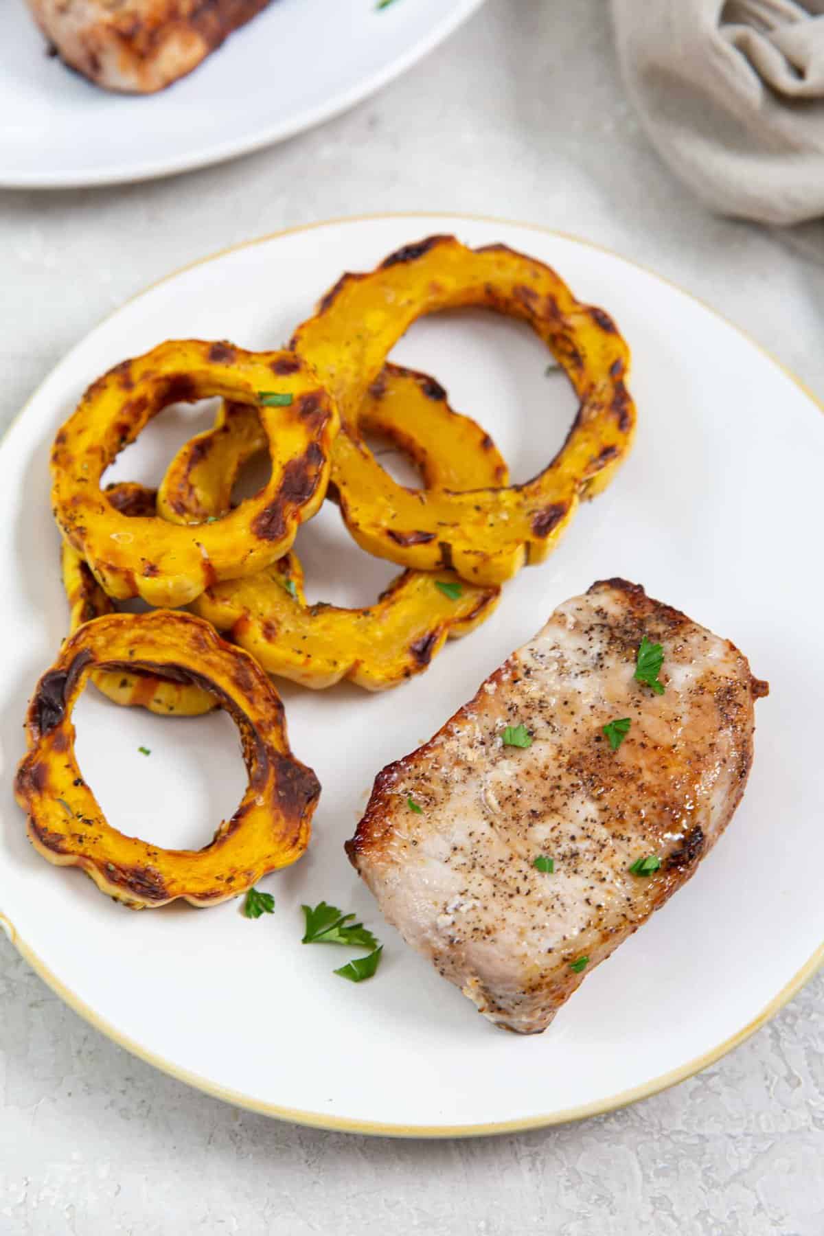 Cooked pork chop on a plate, garnished with parsley.