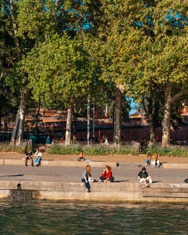 people sittiing along the toulouse riverfront