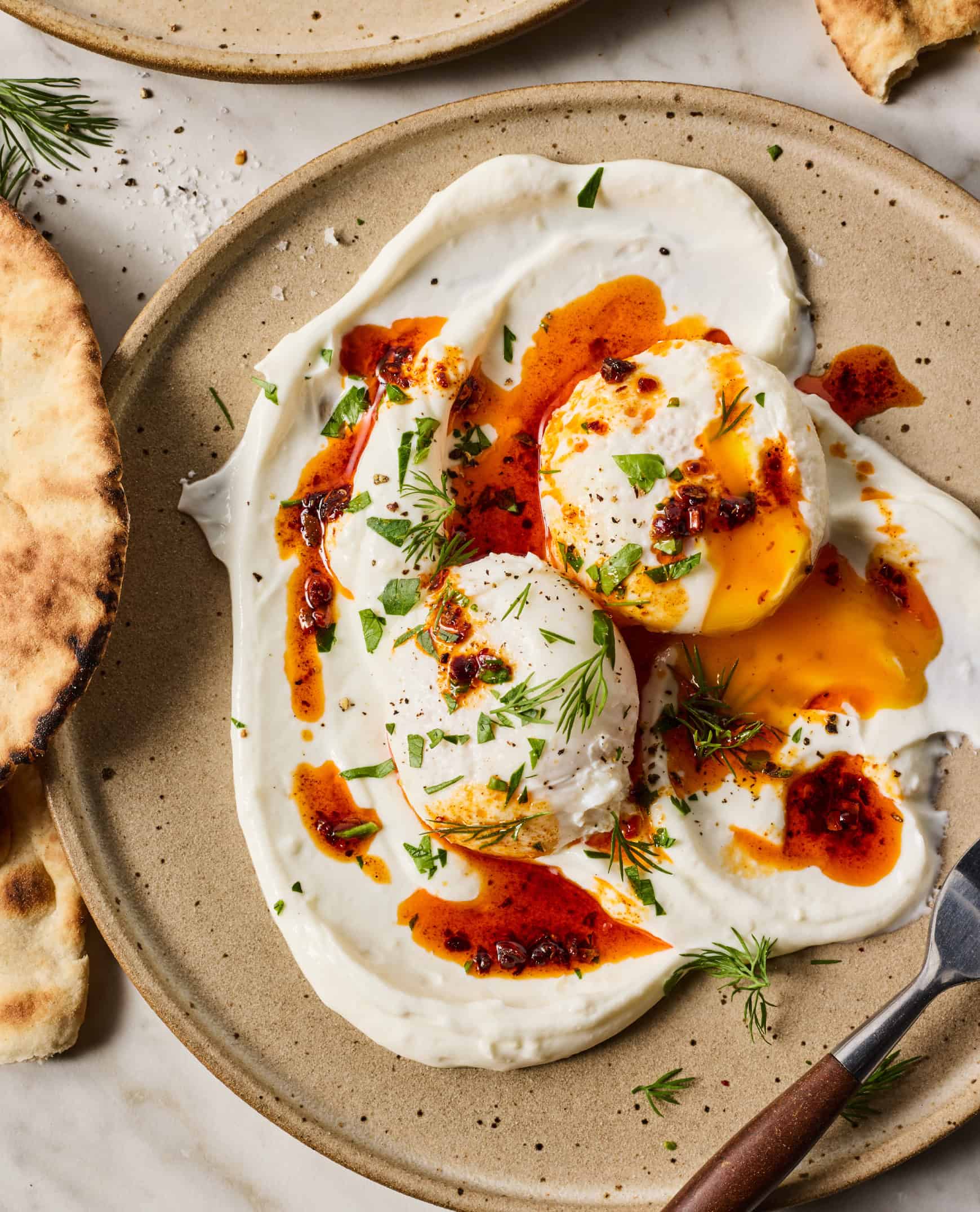 Turkish eggs—poached eggs over yogurt with Aleppo pepper sauce—on plate