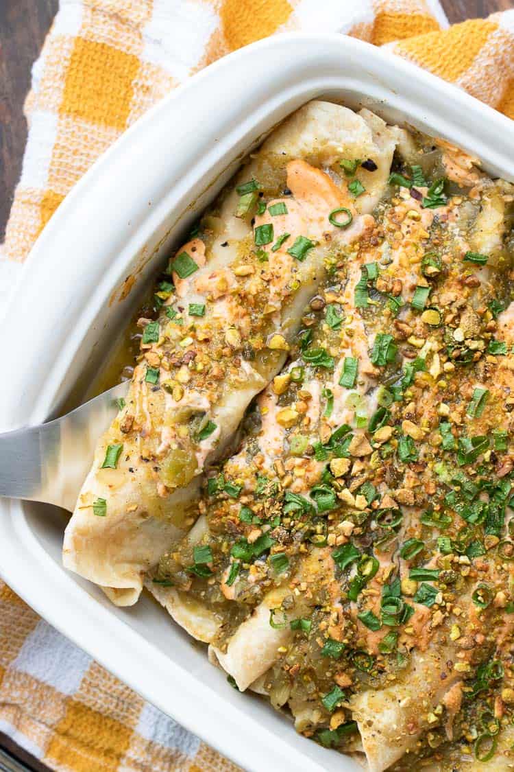 Fall takes on Mexican food like no other! These pumpkin enchiladas will knock your socks off. So flavorful and easy to make, with a perfect creamy twist. #vegan #plantbased #veganmexicanfood #easyveganrecipes Top view of enchiladas topped with green and pink sauces and green onions