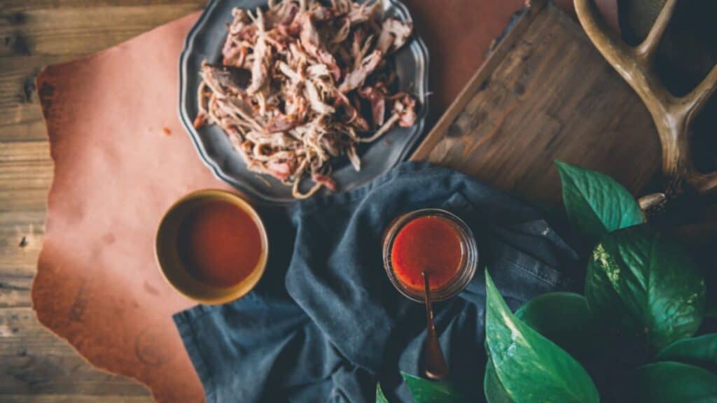 Overheat shot of pulled pork with jar of vinegar sauce. 